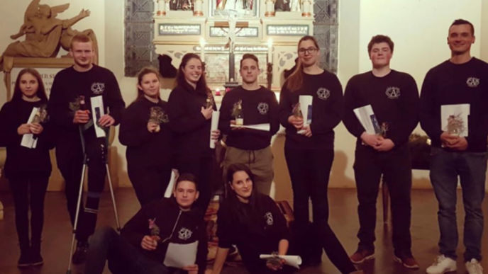 Weihnachtliche Lieder erklingen in der Prietitzer Kirche Eine Gruppe von neun Jugendlichen posiert in einer Kirche, einige halten kleine Geschenke oder Dokumente.